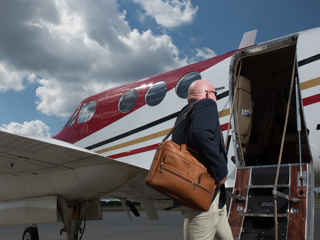 man in blazer carrying leather briefcase