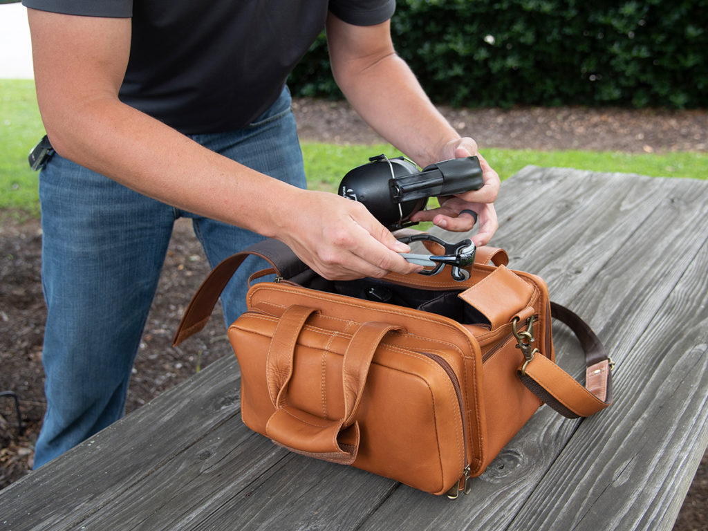 man loading up pistol bag