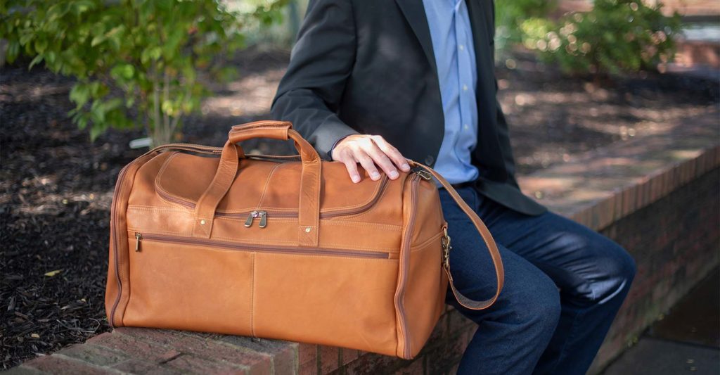 Man sitting on a stone wall with a Sarge leather bag